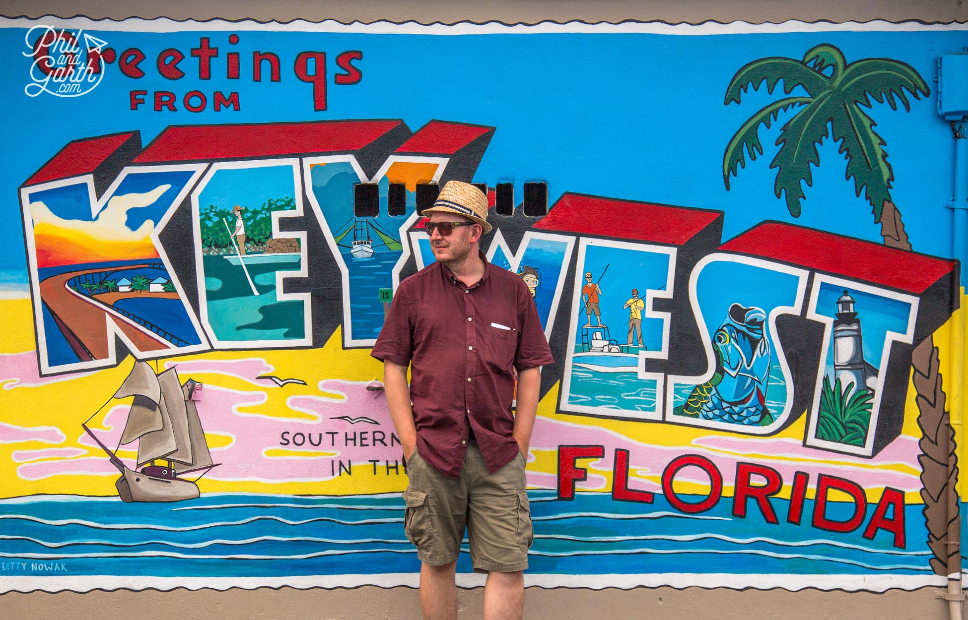 Garth next to the postcard letter mural on Cuban Coffee Queen